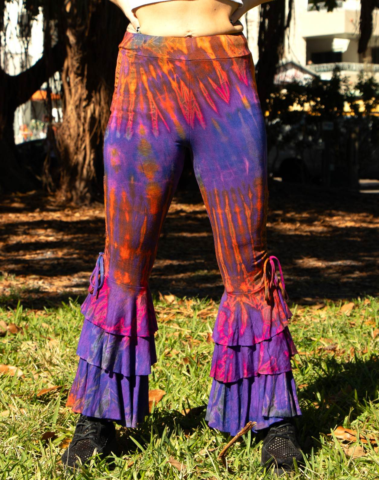 Ruffle bottom pants in vibrant dye patterns with tiered ruffles and a form-fitting design.