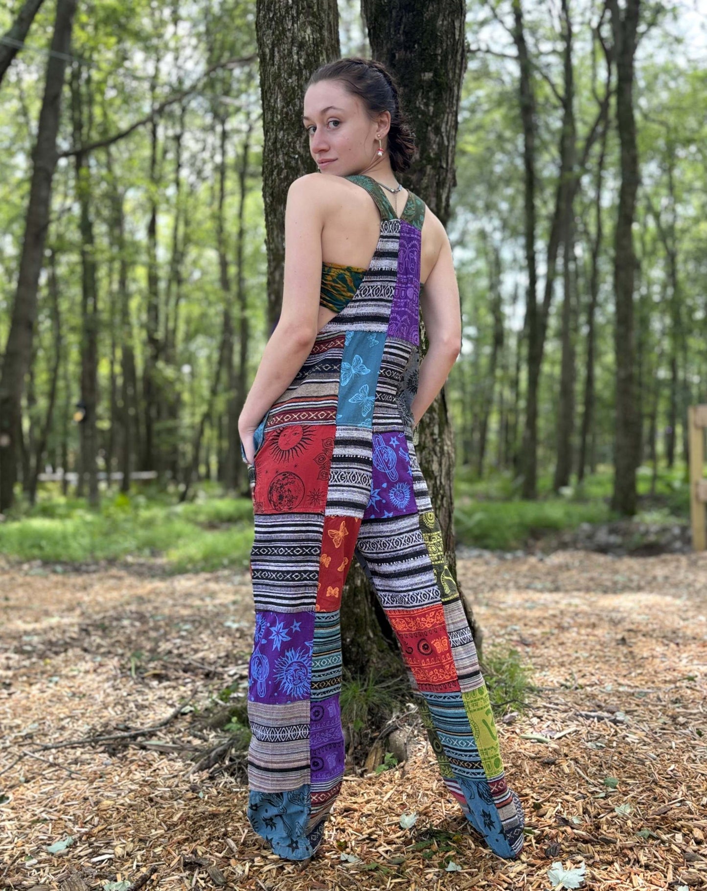 Multi Color & Ikat Patchwork Overalls with adjustable straps in a forest setting.