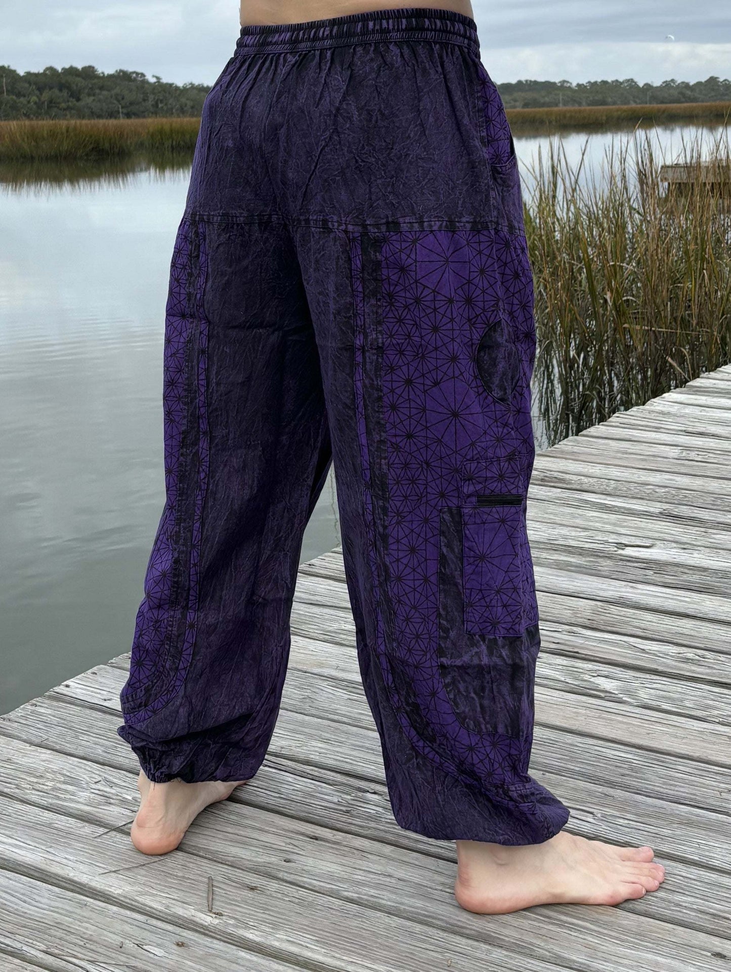 Stone washed pants with six pockets and elastic cuffs on a wooden dock.