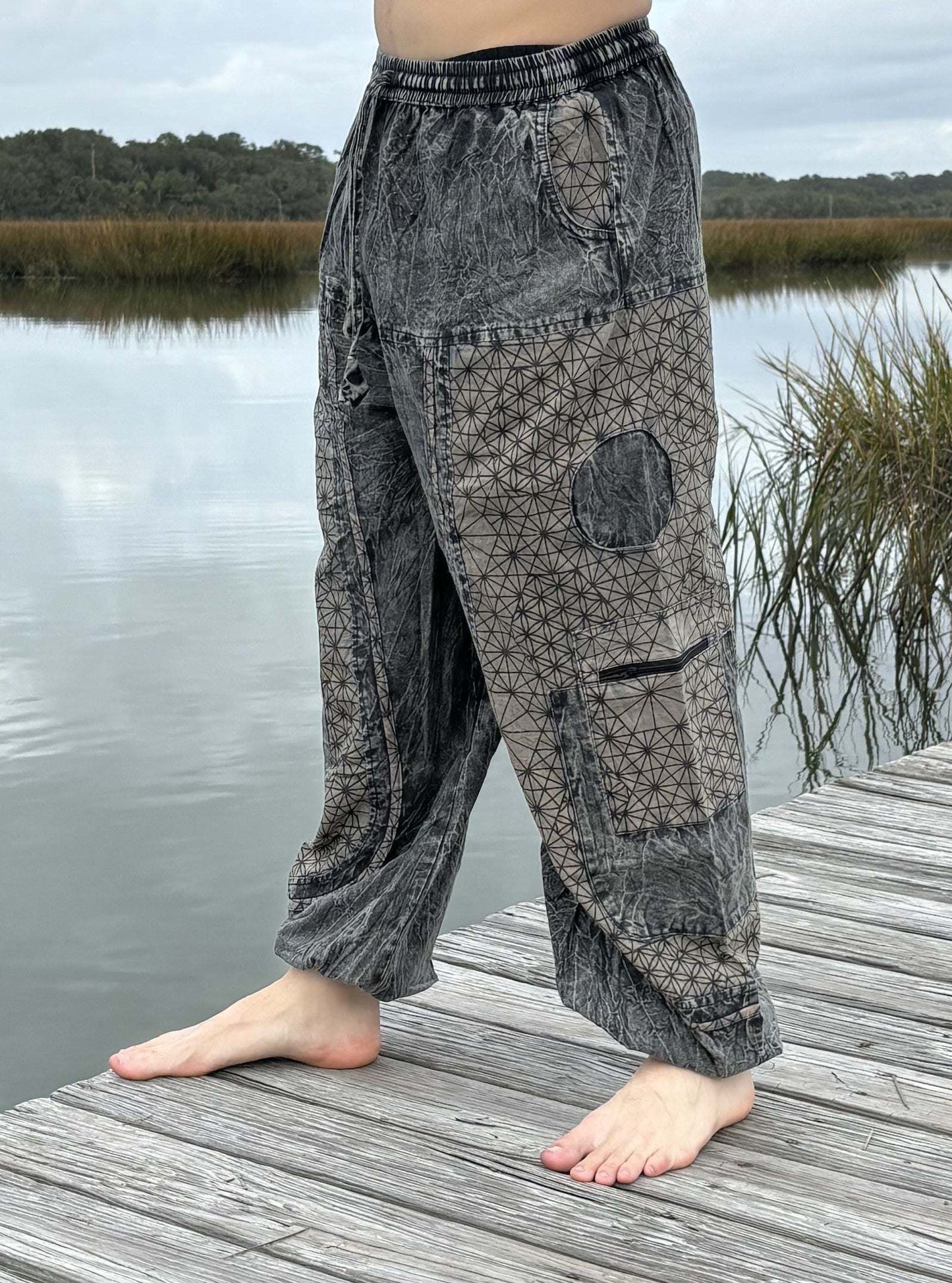 Stone washed pants with six pockets and elastic cuffs by a lake.