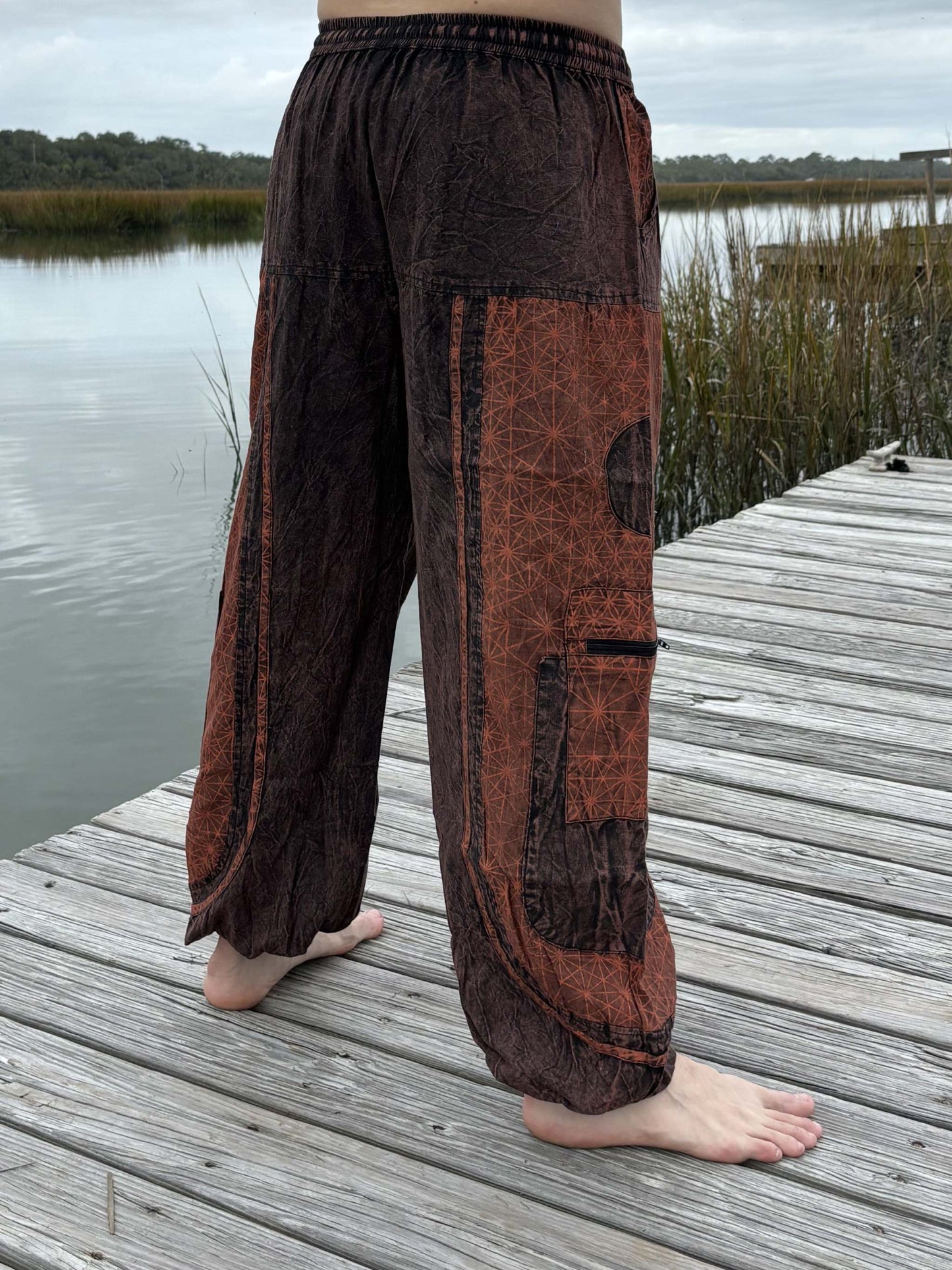 Stone washed pants with elastic cuffs and zipper pockets by a lakeside.