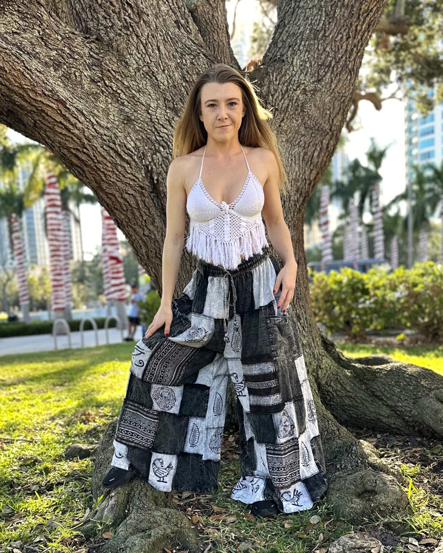 Woman wearing Ares Patchwork Pants with black and white patchwork design, standing by a tree outdoors.