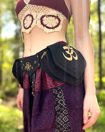 Adjustable Ohm Belt Bag with gold print and metal buckle, worn at a festival.