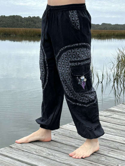 Mushroom Harem Pants with floral embroidery and patchwork design, crafted from 100% handwoven cotton, displaying a unique and fashionable style on a wooden dock by the water.