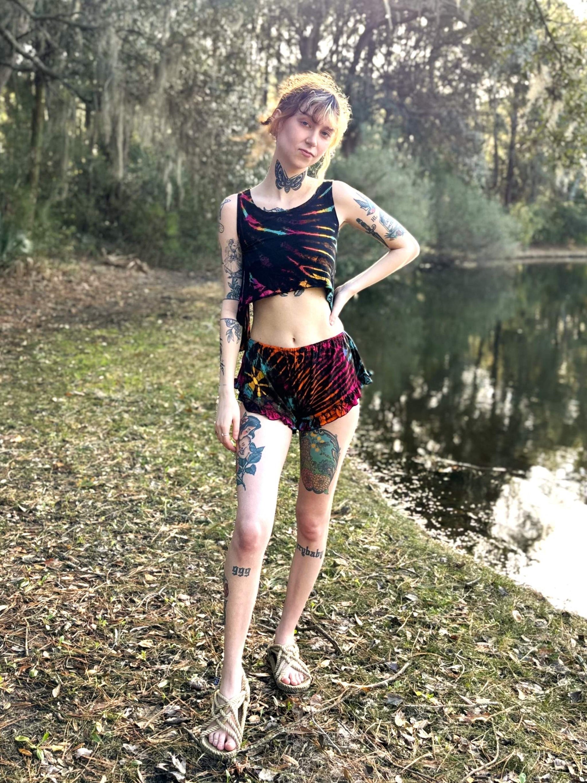 Ruffle booty shorts handcrafted in Thailand, made of rayon and elastic, worn by a tattooed model outdoors.