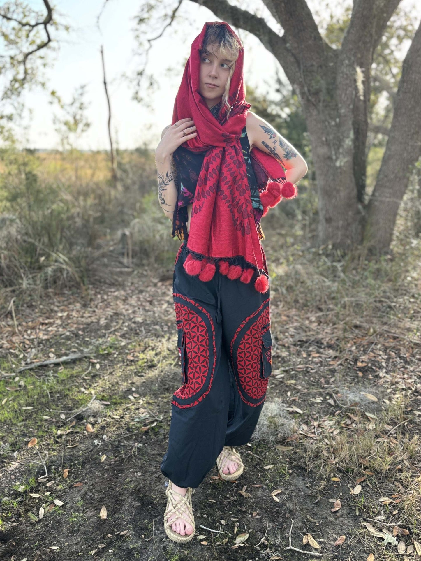 Pom-Pom Pashmina scarf in vibrant red with pom-pom details worn outdoors.