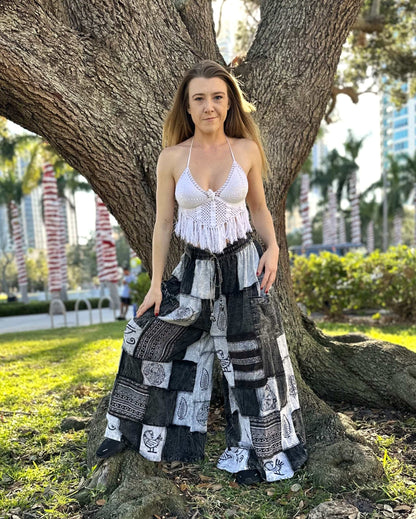 Woman wearing Ares Patchwork Pants with black and white patchwork design, standing by a tree outdoors.